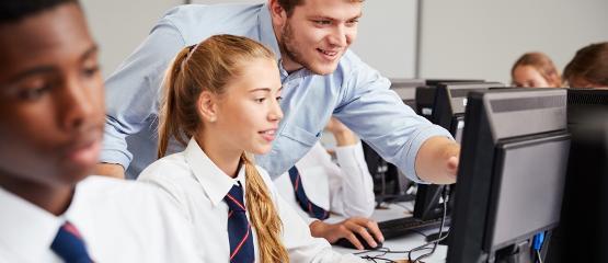 Teenage pupils wearing school uniform studying in ICT class