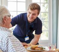 Carer helping elderly gentleman with a meal