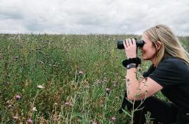  Woman with binoculars looking over long grass