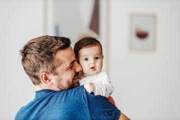 Dad holding baby looking at camera