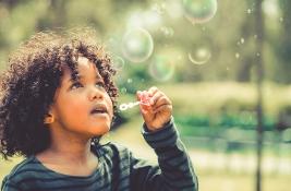 Happy child blowing bubbles in school garden