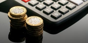 Calculator with small pile of one pound coins next to it